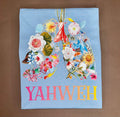 YAHWEH Bloom Premium Tee featuring colorful floral design on a light blue fabric.